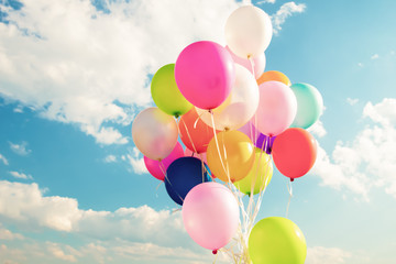 Colorful festive balloons over blue sky with a retro vintage instagram filter effect.