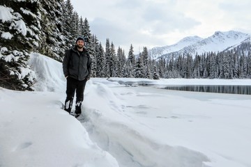 A bearded man snowshoeing around Island Lake in Fernie, British Columbia, Canada.  The majestic winter background is a beautiful place to go hiking or snowshoeing with fresh fallen snow on the trees