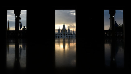 A white Buddhist temple view from a door in an evening