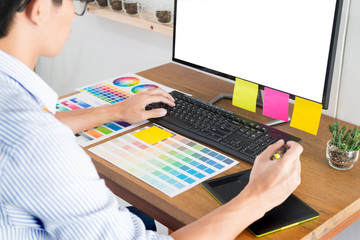 Graphic designer or creative holding Mouse and do his work material color pantone swatch samples art tools at desk in office.