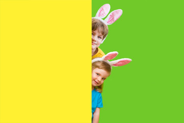 Two cute little kids boy and girl with bunny ears on color background. Happy Easter day!