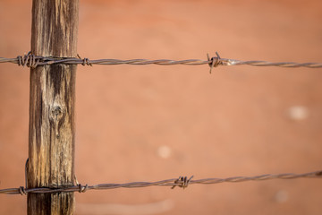 Rusty barb wire fence and old wood poles on Kalahari red sand farm © Anina Lonte