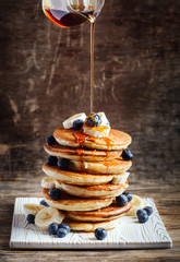 Pancakes with banana, blueberry and maple syrup for a breakfast. - obrazy, fototapety, plakaty