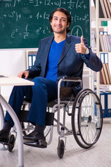 Young handsome man in wheelchair in front of chalkboard 