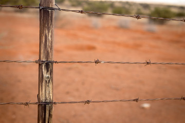 Rusty barb wire fence and old wood poles on Kalahari red sand farm