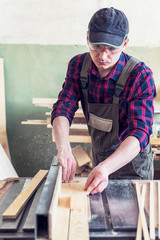 Construction worker cutting wooden board with circular saw