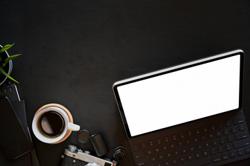 Minimal leather dark desk workspace with tablet, coffee mug, vintage camera and copy space