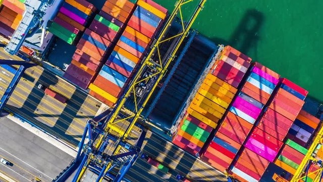Container cargo freight ship with working crane bridge discharge at container terminal, Aerial top view container ship at deep sea port.