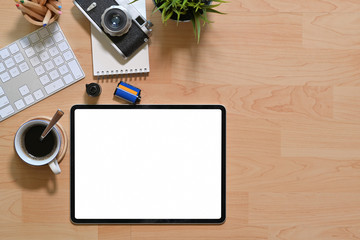 Workplace office wooden desk with blank screen tablet, camera, films and office supplies