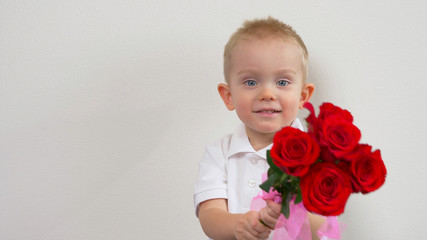 Cute kid ( two years old child)  holding the bouquet of red roses, smiling and looking at camera. Congratulations mother, womens, valentines day concept