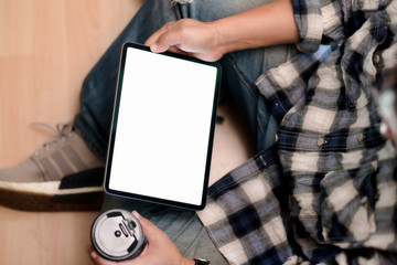 Naklejka premium Top view young man using tablet while sitting on the floor.