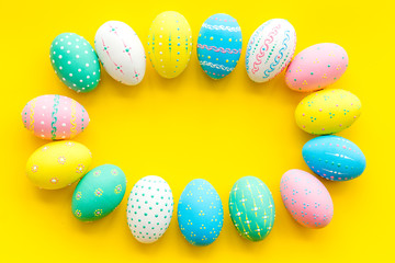 Colorful Easter eggs frame on yellow background top view space for text