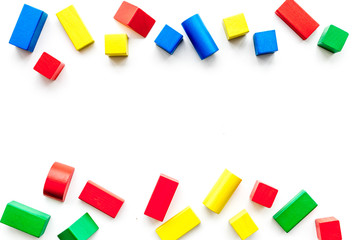Construction game for kids. Wooden building blocks, toy bricks on white background top view copy space border