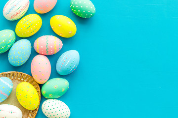 Easter traditions. Colorful Easter eggs in basket on blue background top view space for text border