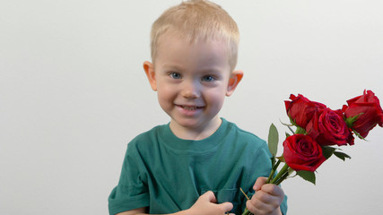 Cute kid ( two years old child)  holding the bouquet of red roses, smiling and looking at camera. Congratulations mother, womens, valentines day concept