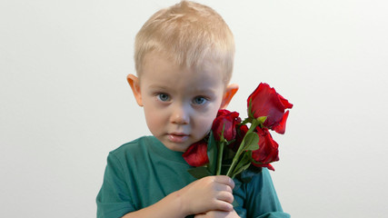 Cute kid ( two years old child)  holding the bouquet of red roses, smiling and looking at camera. Congratulations mother, womens, valentines day concept