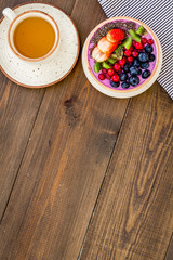 Healthy vegetarian breakfast. Acai smoothie bowl with fresh fruits, berries, chia seeds on dark wooden background top view copy space
