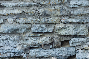 Old grey rough stone wall close-up texture background, selective focus, shallow DOF
