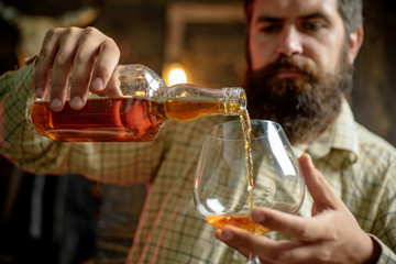 Degustation, tasting. Man with beard holds glass of brandy.
