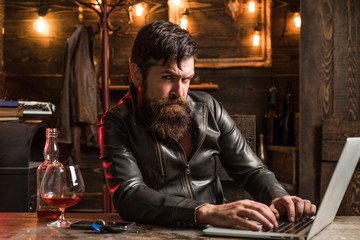 Portrait of a handsome man with beard. Brutality and masculine concept. Barbershop, shaving.Macho is drinking by his laptop. Doubt. Thinking.