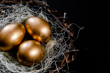 Golden Easter Eggs in birds Nest on black background. Easter Holiday concept abstract background copyspace top view several objects. Close up view