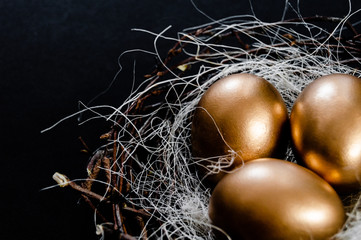 Golden Easter Eggs in birds Nest on black background. Easter Holiday concept abstract background copyspace top view several objects. Close up view