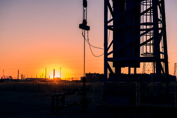 Oil pumps are running in the sunset at the oil field. The outline of the pumping unit.