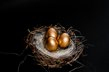 Golden Easter Eggs in birds Nest on black background. Easter Holiday concept abstract background copyspace top view several objects.