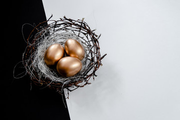 Golden Easter Eggs in birds Nest on black and white abstract background. Easter Holiday concept ...