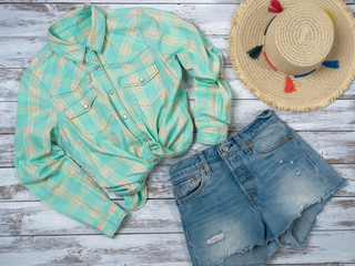Womens clothing, accessories (plaid shirt, denim shorts, straw hat). Fashion outfit, spring summer collection. Shopping concept. Flat lay, top down view