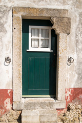 Green door in stone wall of old house in Obidos Portugal