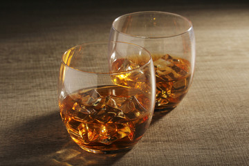 Two glasses with whiskey with ice cubes