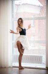 Fototapeta na wymiar Girl ballerina standing near the window in the studio