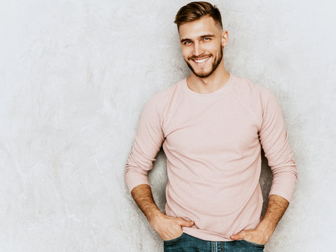 Portrait of handsome smiling hipster lumbersexual businessman model wearing casual summer pink clothes. Fashion stylish man posing against gray wall