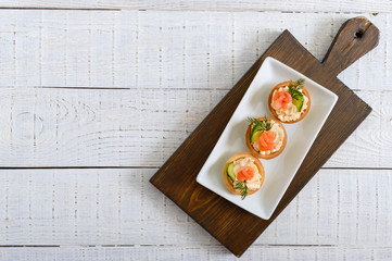 Tartlets with cream cheese and salted salmon on a white plate. Tasty light snack for a party....