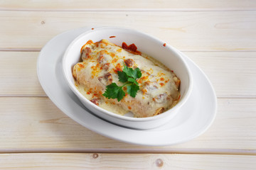Rolled pancakes with ham baked in oven with cheese topping