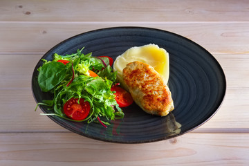 Fried chicken patty with mashed potato and fresh arugula, tomato and spinach