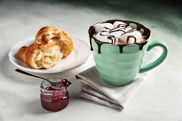 Cup of hot cacao drink with jam in jar on light table