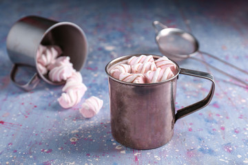 Mug of hot cacao drink with marshmallows on color table