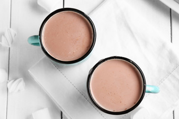 Mugs of hot cacao drink on white table