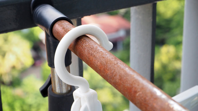 white Hangers hang on rusted clothes rails.