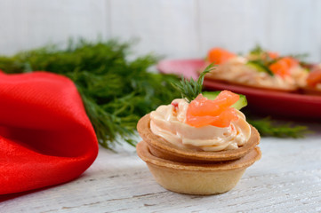 Tartlets with cream cheese and salted salm on a white wooden background. Tasty light snack for a party. Finger Food.