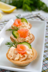Tartlets with cream cheese and salted salmon on a white plate. Tasty light snack for a party. Finger Food.