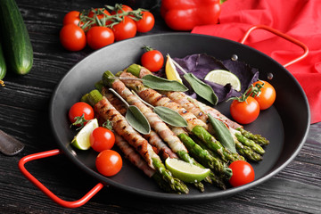 Pan with bacon wrapped asparagus on wooden table