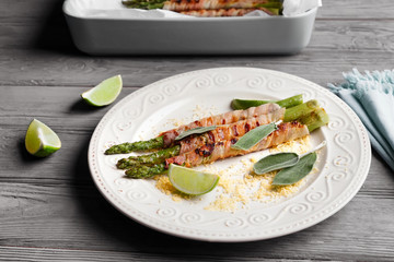 Plate with bacon wrapped asparagus on wooden table