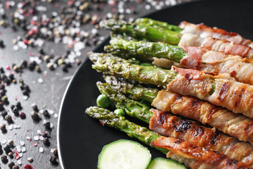 Plate with bacon wrapped asparagus on grey table, closeup