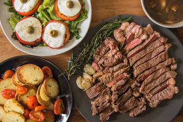 Beef steak with garlic, rosemary, thyme on wooden background 