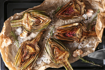 Tasty cooked artichokes on baking sheet