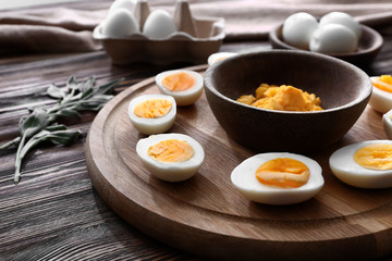 Board with hard-boiled cut eggs and mashed yolk on wooden table