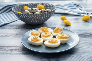 Plate with tasty deviled eggs on wooden table